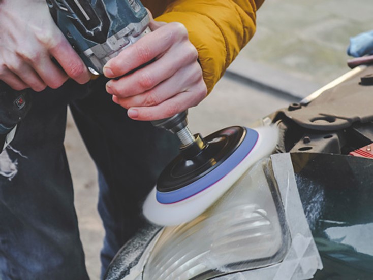 A person using a power tool to polish a car